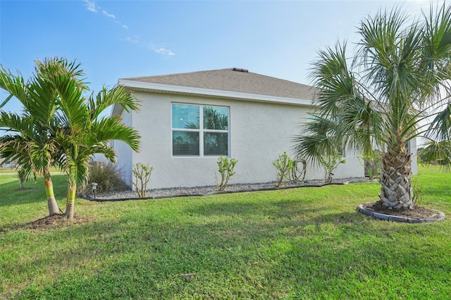 view of side of home featuring stucco siding and a lawn