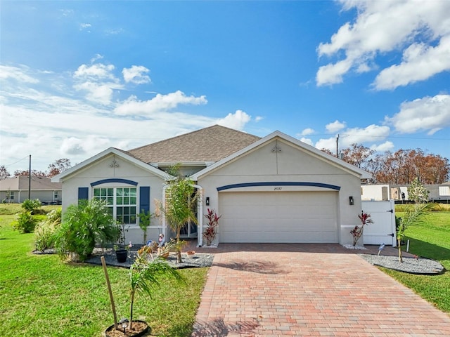 single story home with decorative driveway, a front yard, an attached garage, and stucco siding
