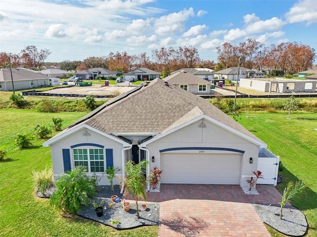 ranch-style home with a residential view, an attached garage, roof with shingles, and decorative driveway