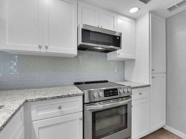 13281 Whitehaven Ln Unit 404, Fort Myers, FL 33966 - kitchen with appliances with stainless steel finishes, white cabinets, decorative backsplash, light stone countertops, and recessed lighting