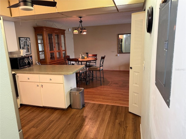 21260 Brinson Ave Unit 110, Port Charlotte, FL 33952 - kitchen featuring black microwave, dark wood finished floors, a peninsula, and white cabinets