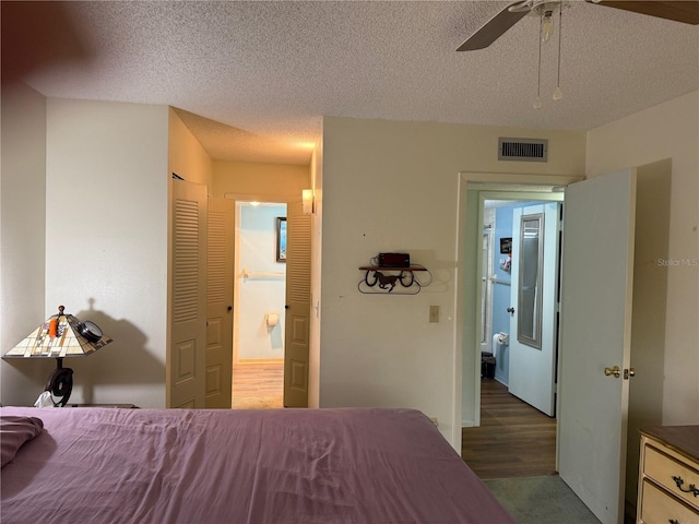 21260 Brinson Ave Unit 110, Port Charlotte, FL 33952 - bedroom featuring a textured ceiling, ensuite bath, ceiling fan, and wood finished floors