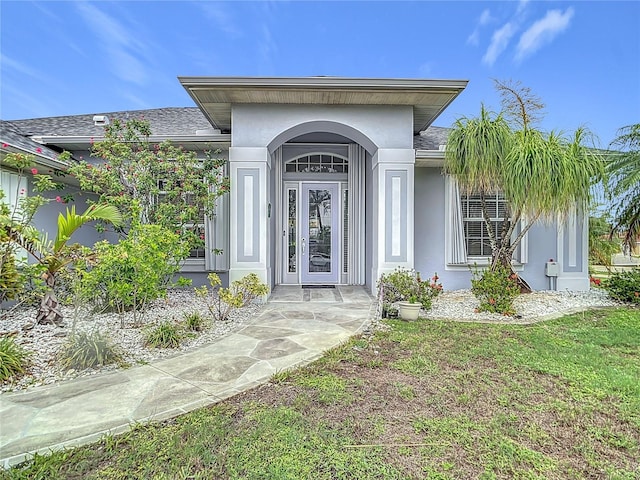 1007 Comstock St, Port Charlotte, FL 33952 - view of exterior entry with stucco siding and roof with shingles
