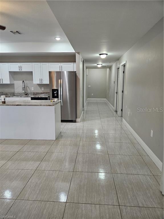 4916/4918 24th St SW, Lehigh Acres, FL 33973 - kitchen with stainless steel fridge with ice dispenser, white cabinetry, baseboards, a sink, and light countertops