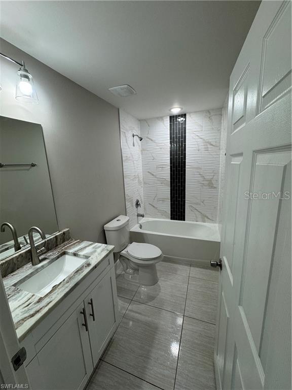 4916/4918 24th St SW, Lehigh Acres, FL 33973 - bathroom featuring toilet, vanity, and washtub / shower combination