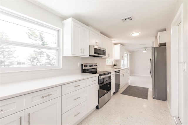 444 Edgewood Rd, Venice, FL 34293 - kitchen featuring appliances with stainless steel finishes, white cabinets, ceiling fan, and healthy amount of natural light