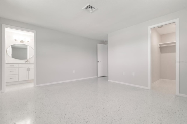 444 Edgewood Rd, Venice, FL 34293 - unfurnished bedroom featuring dark speckled floor, a spacious closet, and connected bathroom