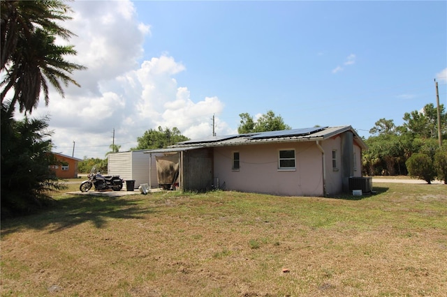 28024 Cleveland Ave, Punta Gorda, FL 33982 - rear view of house with central AC, roof mounted solar panels, a yard, and stucco siding