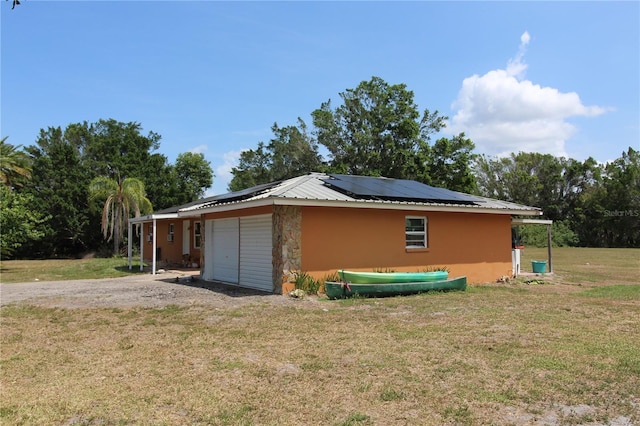 28024 Cleveland Ave, Punta Gorda, FL 33982 - view of side of home with an attached garage, a lawn, solar panels, and stone siding