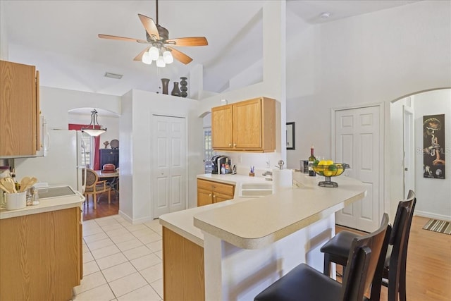 3322 Hampton St, Port Charlotte, FL 33948 - kitchen featuring a peninsula, a kitchen breakfast bar, light countertops, ceiling fan, and light tile patterned flooring