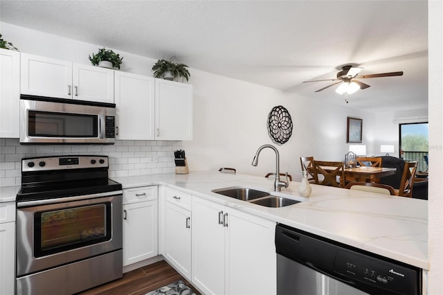 175 Kings Hwy Unit 625, Punta Gorda, FL 33983 - kitchen featuring appliances with stainless steel finishes, a sink, decorative backsplash, a peninsula, and white cabinetry