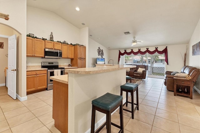 7280 Muncey Rd, North Port, FL 34291 - kitchen featuring appliances with stainless steel finishes, light tile patterned floors, light countertops, ceiling fan, and a kitchen breakfast bar