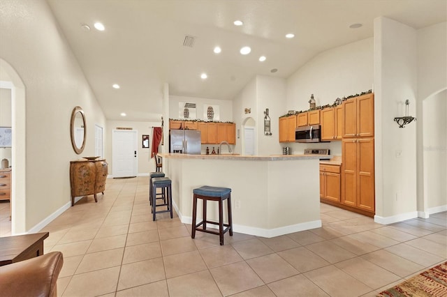7280 Muncey Rd, North Port, FL 34291 - kitchen featuring stainless steel appliances, arched walkways, light tile patterned flooring, a center island with sink, and a breakfast bar area