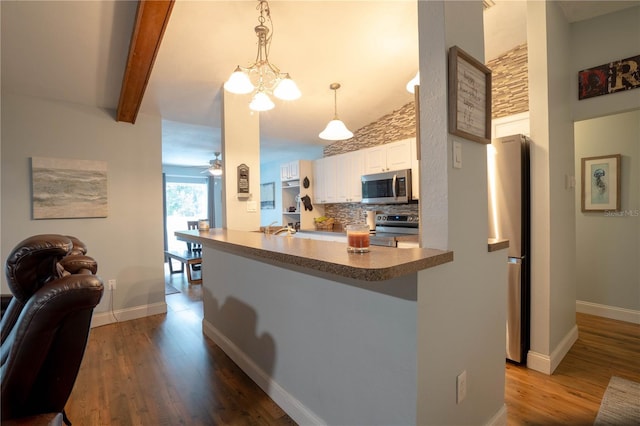 21220 Pemberton Ave, Port Charlotte, FL 33952 - kitchen with appliances with stainless steel finishes, wood finished floors, white cabinets, tasteful backsplash, and open floor plan