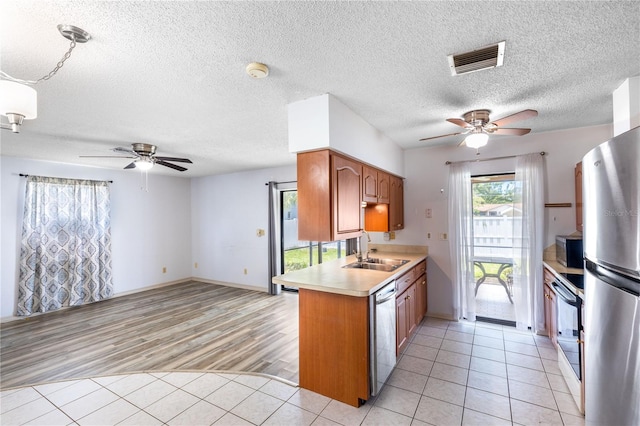 3242 Nocturne Rd, Venice, FL 34293 - kitchen with ceiling fan, stainless steel appliances, light countertops, brown cabinets, and a textured ceiling