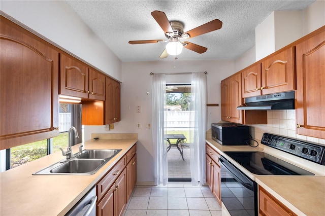 3242 Nocturne Rd, Venice, FL 34293 - kitchen featuring appliances with stainless steel finishes, under cabinet range hood, light countertops, healthy amount of natural light, and a textured ceiling