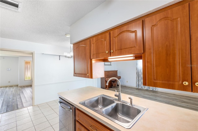 3242 Nocturne Rd, Venice, FL 34293 - kitchen with stainless steel dishwasher, light countertops, brown cabinets, a textured ceiling, and light tile patterned floors