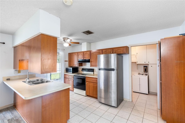 3242 Nocturne Rd, Venice, FL 34293 - kitchen with appliances with stainless steel finishes, under cabinet range hood, a peninsula, washer and dryer, and a ceiling fan