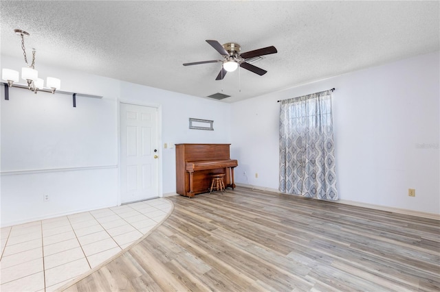 3242 Nocturne Rd, Venice, FL 34293 - unfurnished living room with light wood-style flooring, a textured ceiling, ceiling fan, and a chandelier