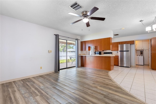 3242 Nocturne Rd, Venice, FL 34293 - kitchen featuring freestanding refrigerator, light countertops, brown cabinetry, light wood finished floors, and a textured ceiling