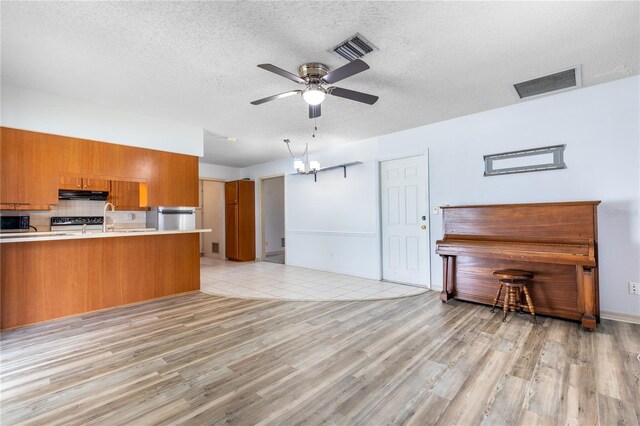 3242 Nocturne Rd, Venice, FL 34293 - kitchen featuring brown cabinets, a ceiling fan, under cabinet range hood, light countertops, and light wood-style flooring