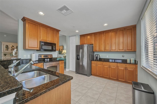 90 Vivante Blvd Unit 202, Punta Gorda, FL 33950 - kitchen featuring appliances with stainless steel finishes, recessed lighting, light tile patterned floors, dark stone counters, and brown cabinetry