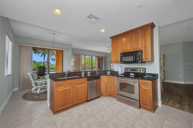 90 Vivante Blvd Unit 202, Punta Gorda, FL 33950 - kitchen with appliances with stainless steel finishes, a peninsula, brown cabinets, dark stone counters, and recessed lighting