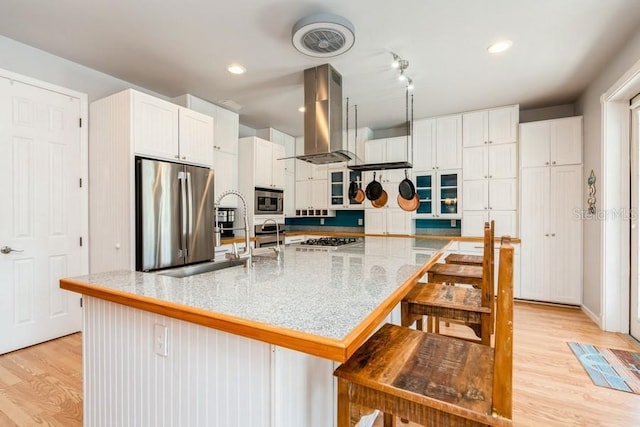 7424 Acorn Blvd, Punta Gorda, FL 33982 - kitchen featuring island range hood, appliances with stainless steel finishes, light wood finished floors, white cabinetry, and a kitchen breakfast bar