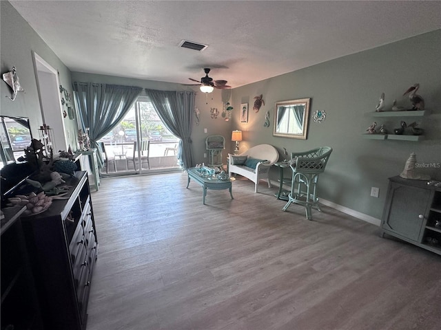 93 Boundary Blvd Unit 303, Rotonda West, FL 33947 - living area featuring wood finished floors, ceiling fan, baseboards, and a textured ceiling