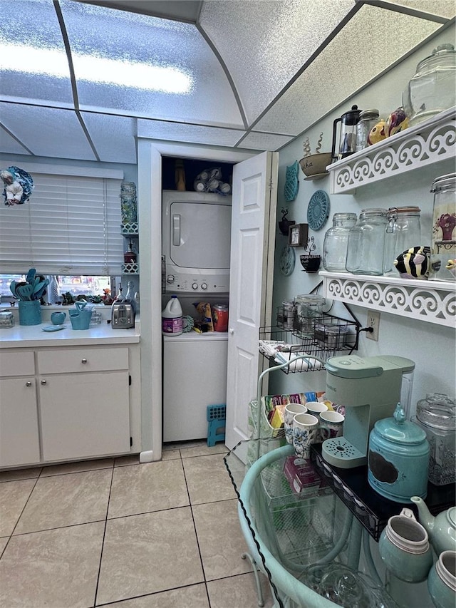93 Boundary Blvd Unit 303, Rotonda West, FL 33947 - kitchen featuring estacked washer and dryer, light tile patterned flooring, white cabinetry, light countertops, and a drop ceiling