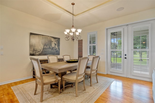 5221 Blackjack Cir, Punta Gorda, FL 33982 - dining space featuring a chandelier, light wood-style flooring, french doors, and a tray ceiling