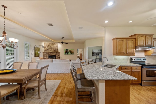 5221 Blackjack Cir, Punta Gorda, FL 33982 - kitchen featuring stainless steel range with electric cooktop, under cabinet range hood, ceiling fan, light wood-style floors, and light stone counters