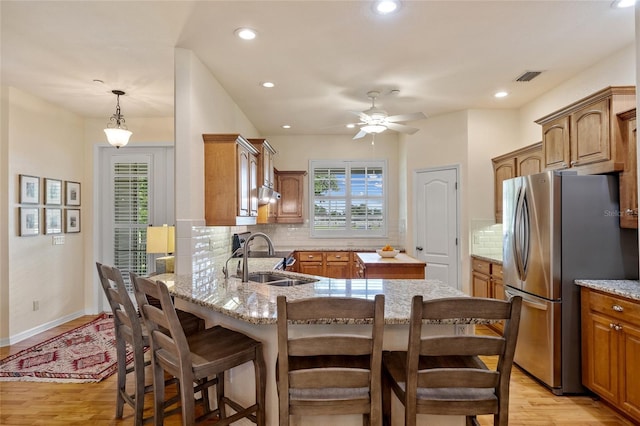5221 Blackjack Cir, Punta Gorda, FL 33982 - kitchen featuring freestanding refrigerator, light wood finished floors, a peninsula, backsplash, and a kitchen bar
