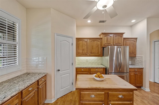 5221 Blackjack Cir, Punta Gorda, FL 33982 - kitchen featuring freestanding refrigerator, light wood-type flooring, brown cabinetry, and light stone counters