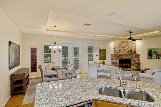 5221 Blackjack Cir, Punta Gorda, FL 33982 - kitchen with a raised ceiling, light wood-type flooring, a fireplace, light stone countertops, and pendant lighting