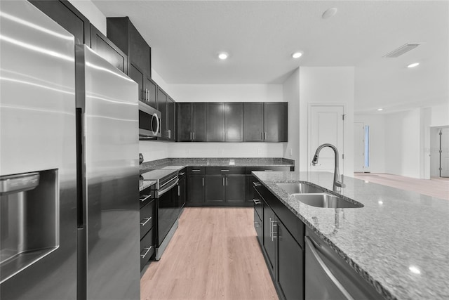 2138 Blaser St, Punta Gorda, FL 33980 - kitchen with appliances with stainless steel finishes, light stone counters, light wood-type flooring, dark cabinets, and recessed lighting