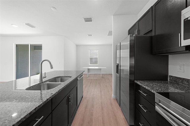 2138 Blaser St, Punta Gorda, FL 33980 - kitchen featuring dark cabinetry, light wood-style flooring, dark stone countertops, and appliances with stainless steel finishes