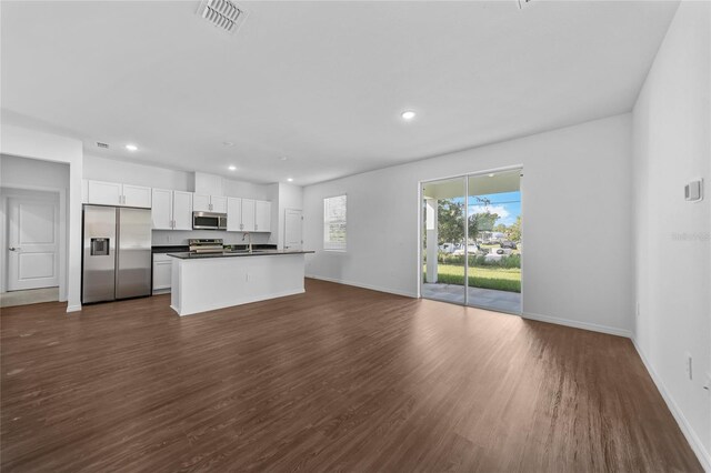 7345 Ellis Ln, Port Charlotte, FL 33981 - kitchen featuring appliances with stainless steel finishes, dark countertops, open floor plan, dark wood-style floors, and white cabinets