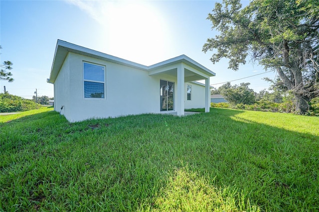 7345 Ellis Ln, Port Charlotte, FL 33981 - rear view of house featuring stucco siding and a yard
