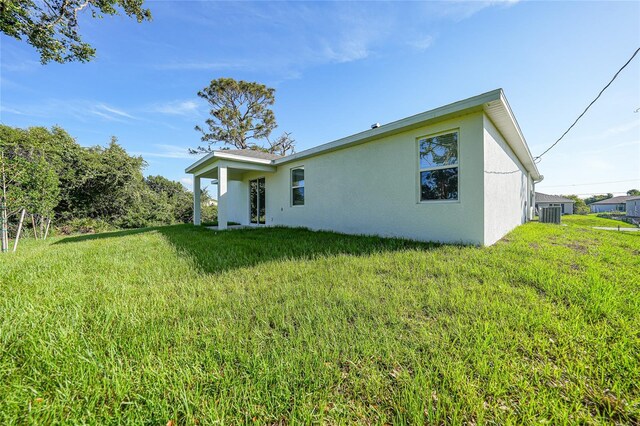 7345 Ellis Ln, Port Charlotte, FL 33981 - back of house with stucco siding and a yard