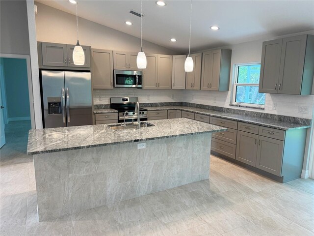 2451 Waller Rd, North Port, FL 34288 - kitchen featuring appliances with stainless steel finishes, gray cabinetry, dark stone counters, a kitchen island with sink, and lofted ceiling