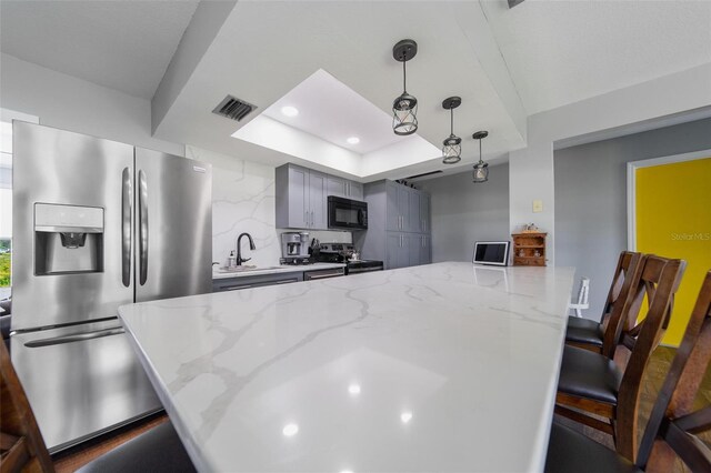 405 Ridgecrest Dr, Punta Gorda, FL 33982 - kitchen with appliances with stainless steel finishes, a sink, a kitchen bar, a tray ceiling, and hanging light fixtures