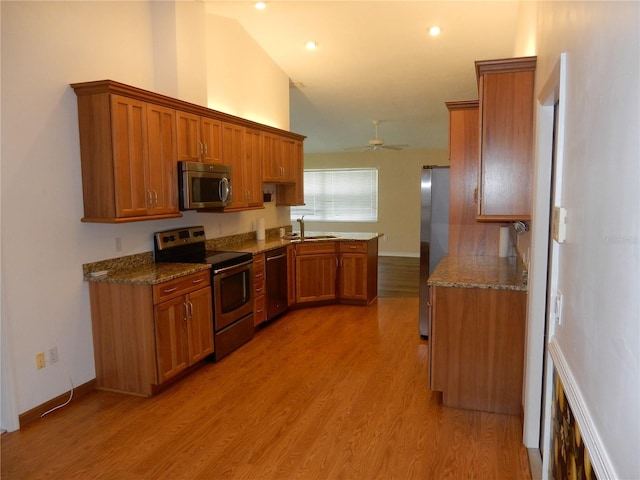 500 Winwood Ct, Port Charlotte, FL 33954 - kitchen featuring appliances with stainless steel finishes, brown cabinetry, stone countertops, light wood-type flooring, and a peninsula