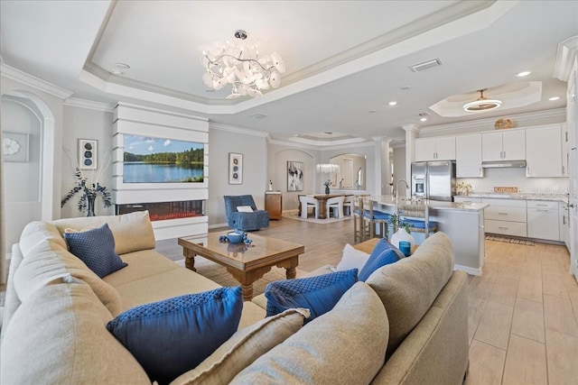 15039 Black Cherry Way, Punta Gorda, FL 33955 - living area with a tray ceiling, arched walkways, a chandelier, crown molding, and light wood finished floors