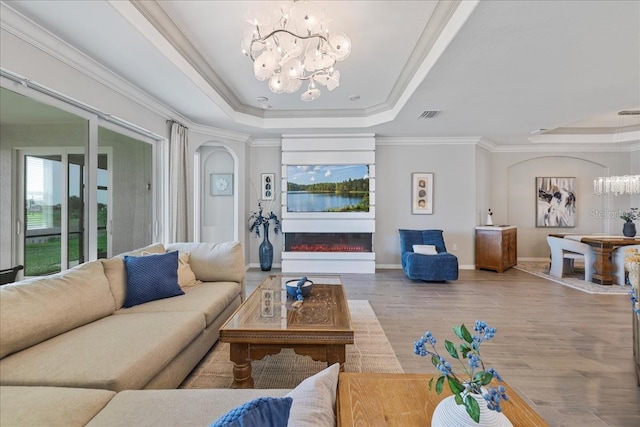15039 Black Cherry Way, Punta Gorda, FL 33955 - living area with a raised ceiling, a chandelier, crown molding, a glass covered fireplace, and wood finished floors
