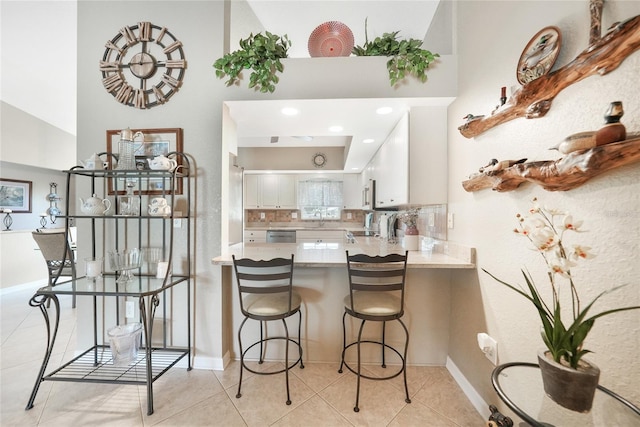 37 Pepe Ct, Punta Gorda, FL 33983 - kitchen featuring white cabinets, a peninsula, tasteful backsplash, light countertops, and a towering ceiling