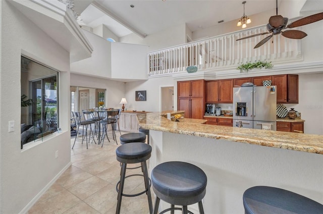 250 Freeport Ct, Punta Gorda, FL 33950 - kitchen with stainless steel fridge, a towering ceiling, ceiling fan, brown cabinetry, and a kitchen bar