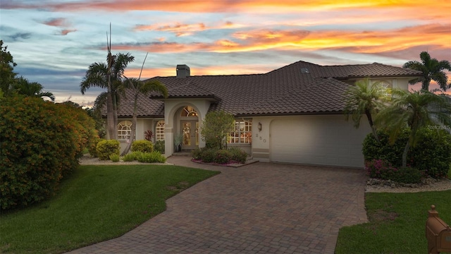 250 Freeport Ct, Punta Gorda, FL 33950 - mediterranean / spanish-style home featuring stucco siding, a chimney, a garage, decorative driveway, and a tiled roof