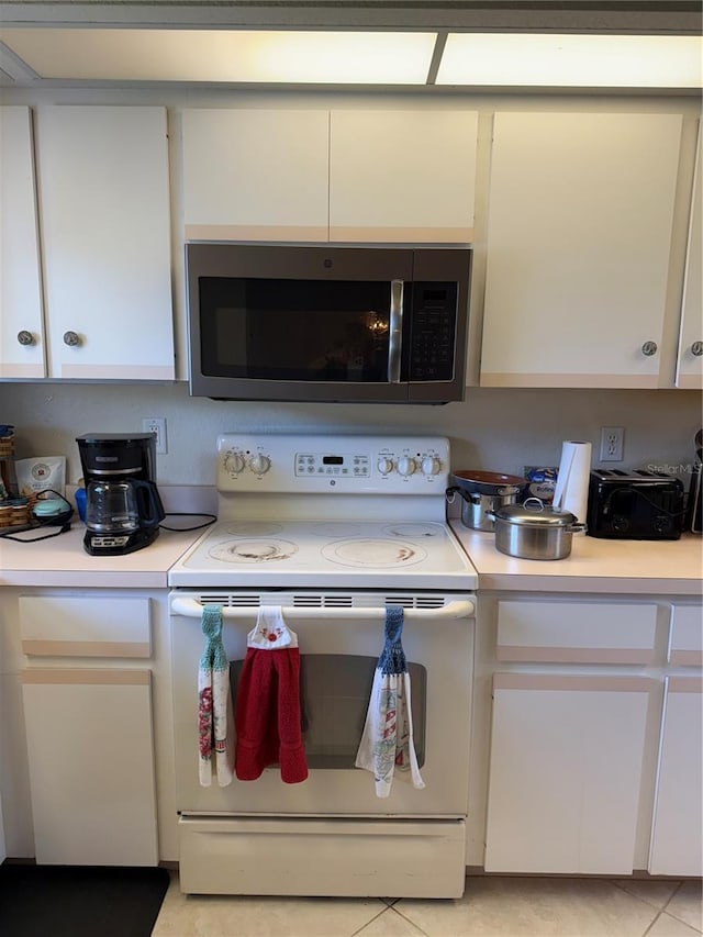 26312 Deep Creek Blvd, Punta Gorda, FL 33983 - kitchen with white range with electric stovetop, stainless steel microwave, light countertops, and white cabinets