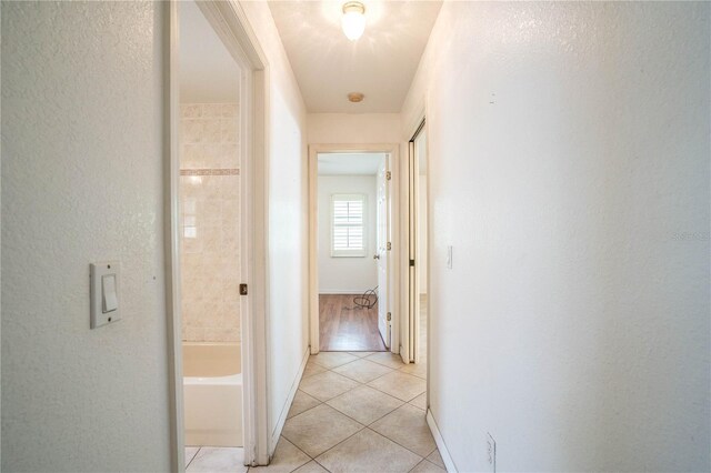 23101 Hillsdale Ave, Port Charlotte, FL 33954 - hallway with light tile patterned floors, a textured wall, and baseboards